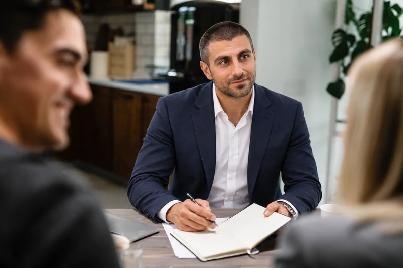 Petros Ttofari discussing property plans with a couple at a table