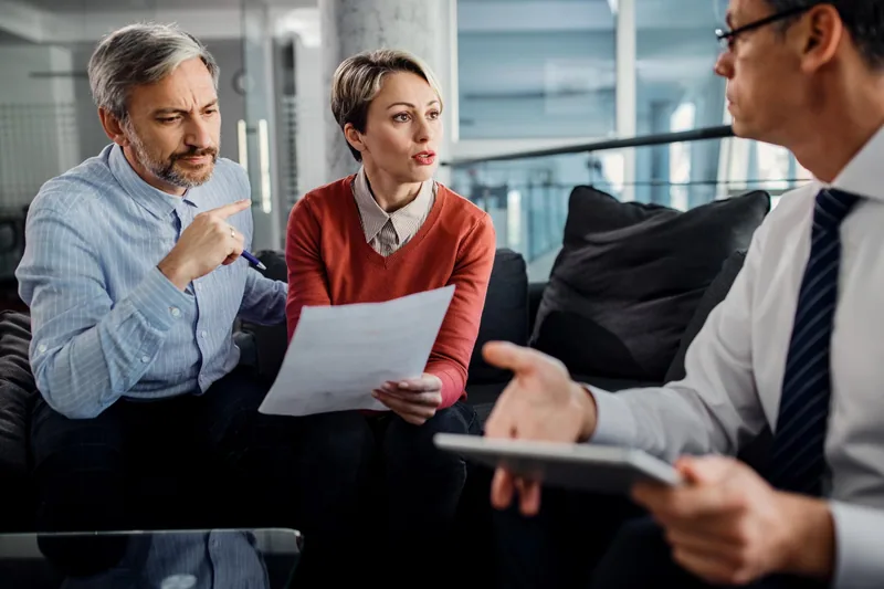 Couple discussing property documents with an adviser